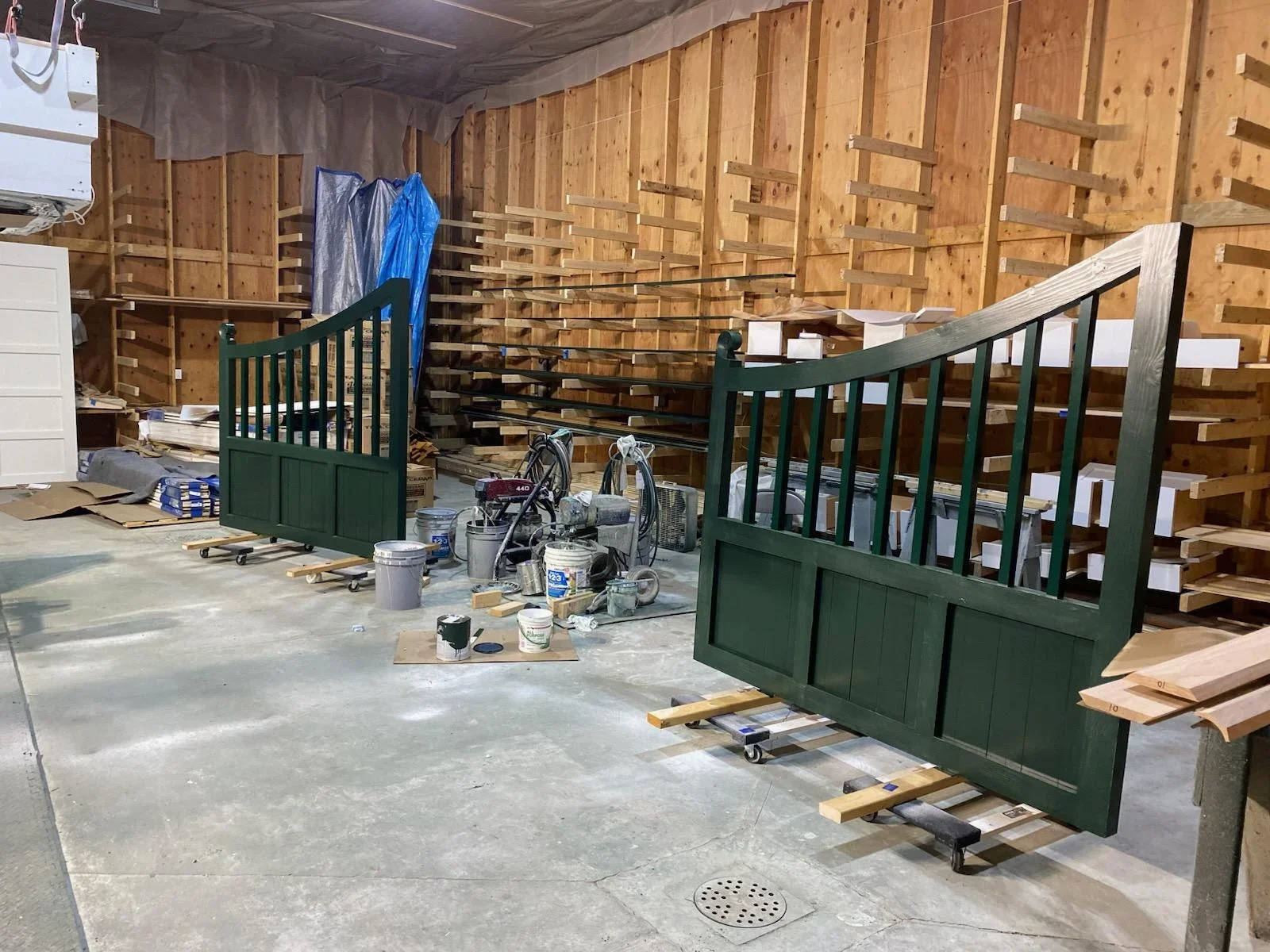 Forest green painted wooden driveway gates with spindle design during finishing in workshop