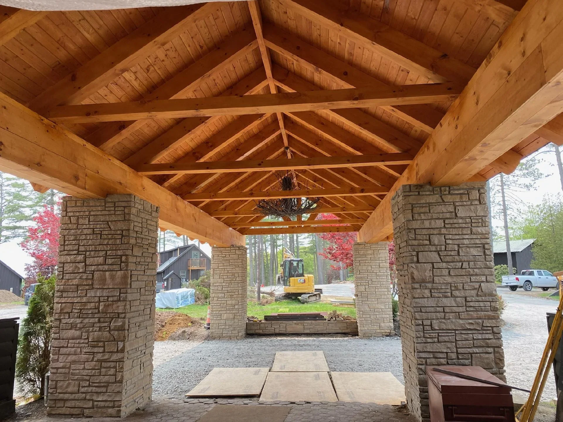Timber frame pergola with stone pillars under construction in residential setting