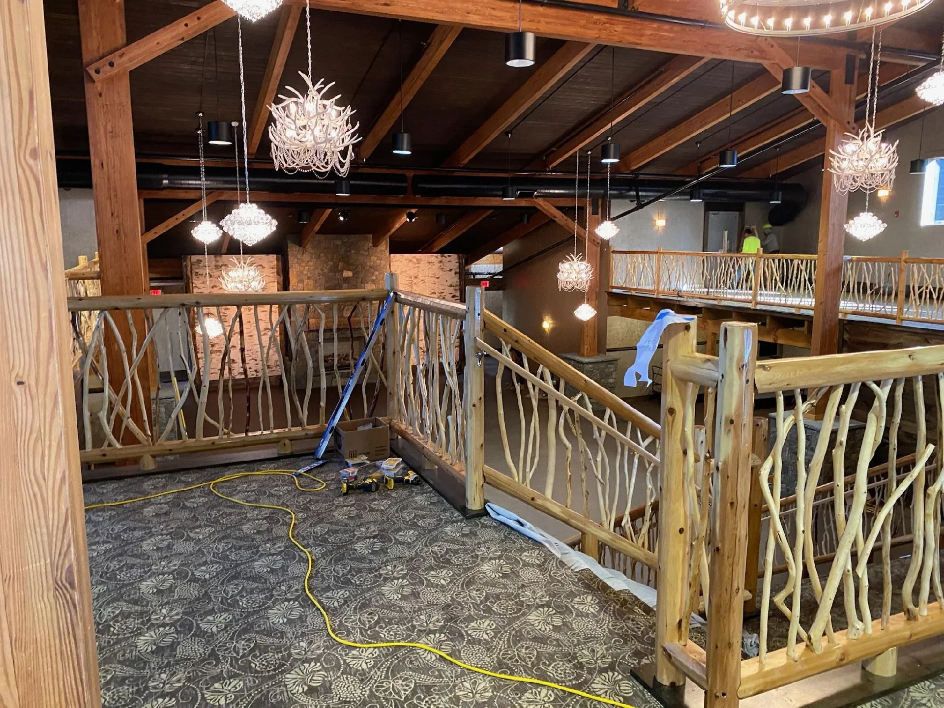 Commercial interior with timber beams, wood railings, and pendant lighting during painting project
