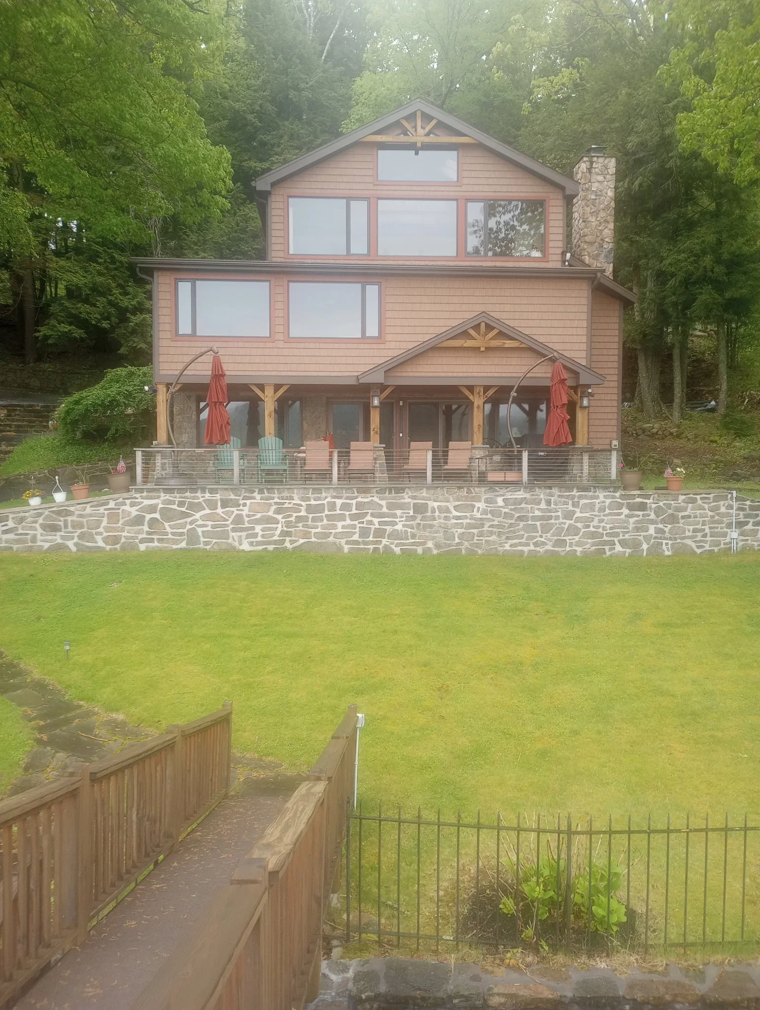 Two-story home with taupe painted siding, covered deck with timber framing, and stone patio