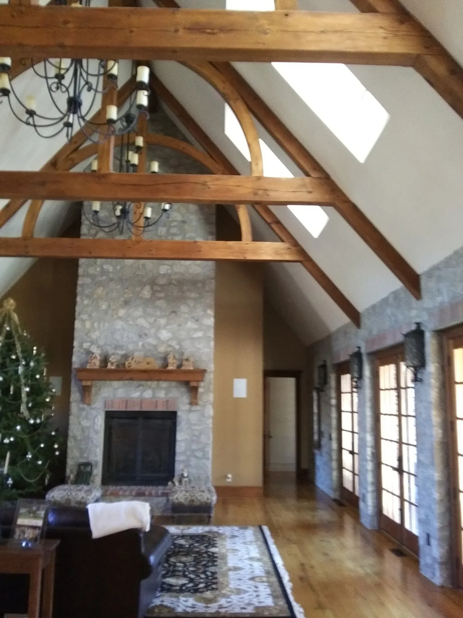 Vaulted ceiling room with exposed wood beams, stone fireplace, and skylights after interior painting