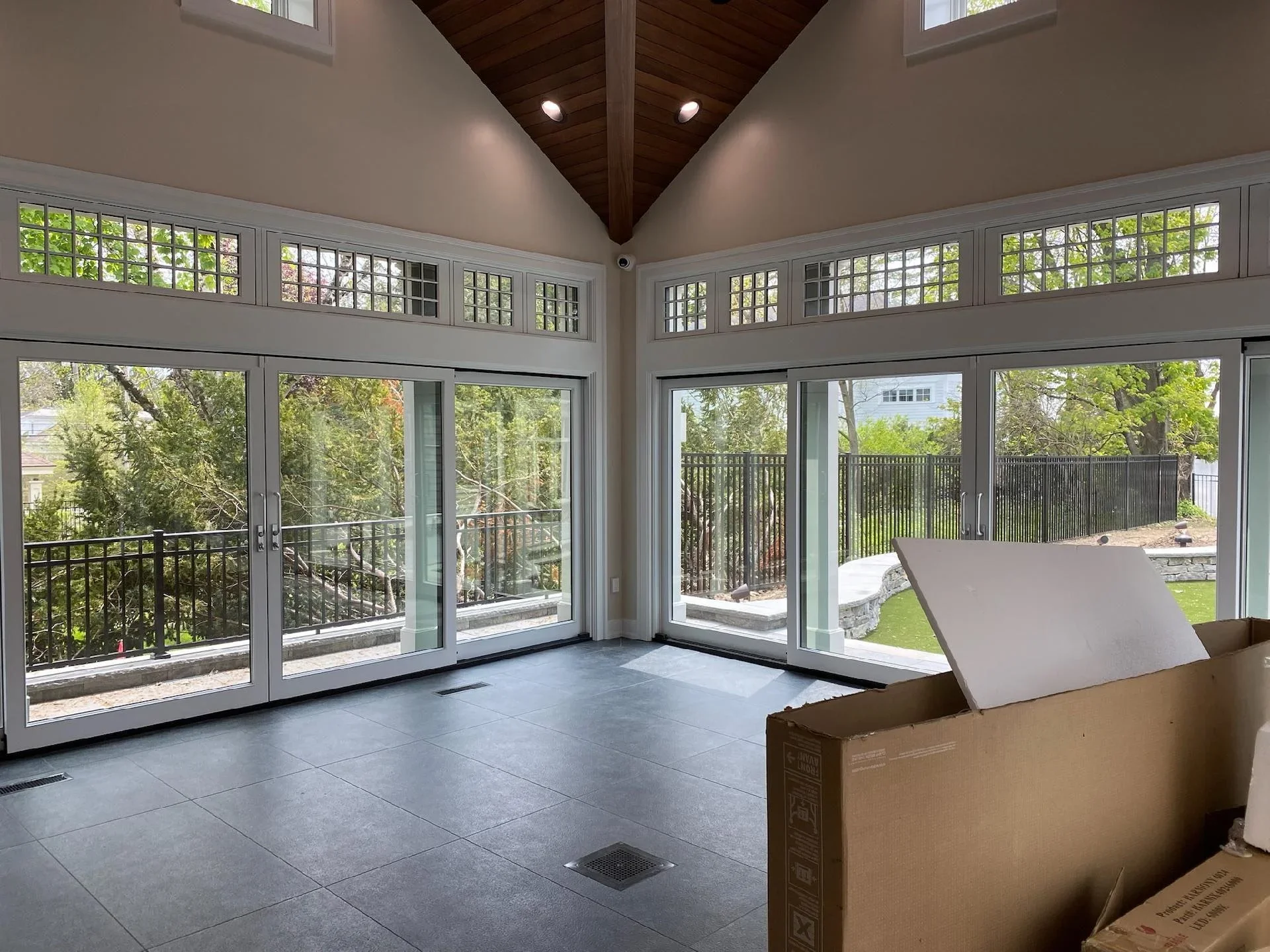 Newly painted sunroom with vaulted ceiling, white trim, and glass doors overlooking landscaped yard