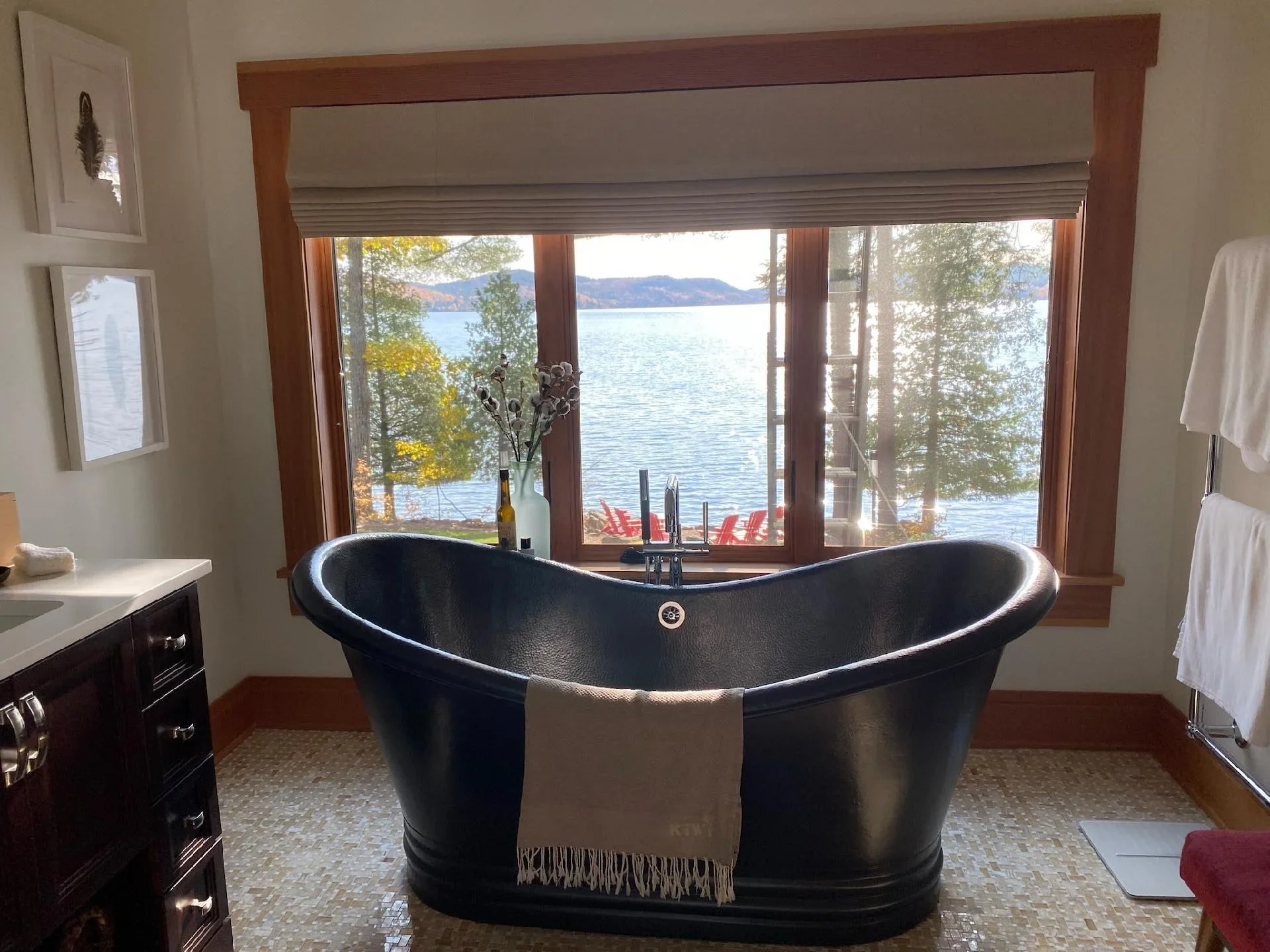 Black soaker tub in luxury bathroom with cream walls, mahogany trim, and lake view windows